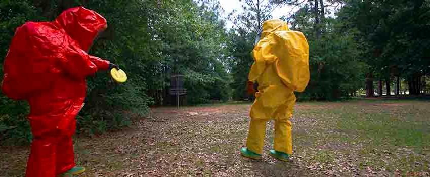 Two men in hazmat suits in disc golf courseTwo men in hazmat suits in front of storage container