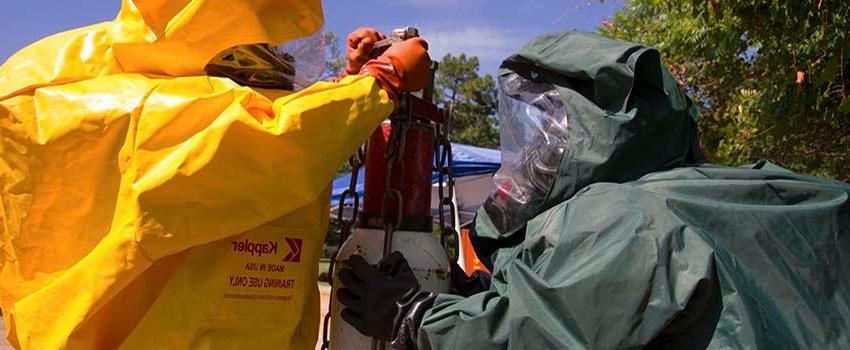 Two men in hazmat suits in working with equiment